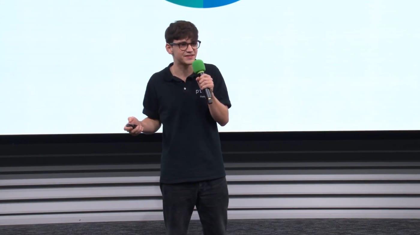 Baptiste pitching Pilea on stage, holding a microphone